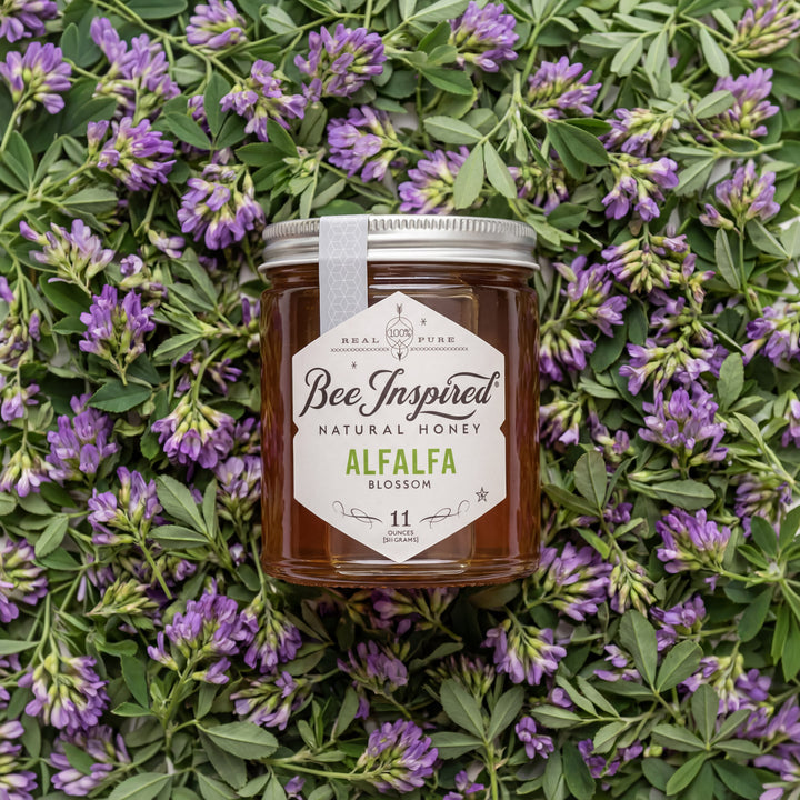 Jar of Bee Inspired honey surrounded by alfalfa flowers