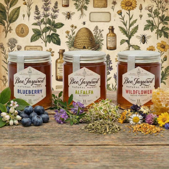 Three jars of 'Bee Inspired' honey on a wooden surface with floral and botanical decorations.