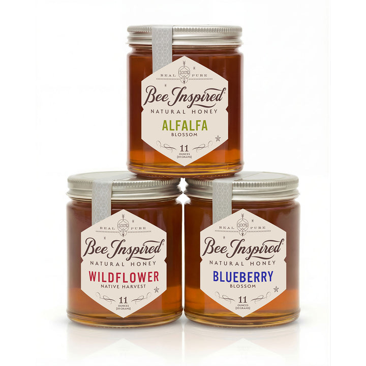 Three jars of 'Bee Inspired' honey with different flavors on a white background