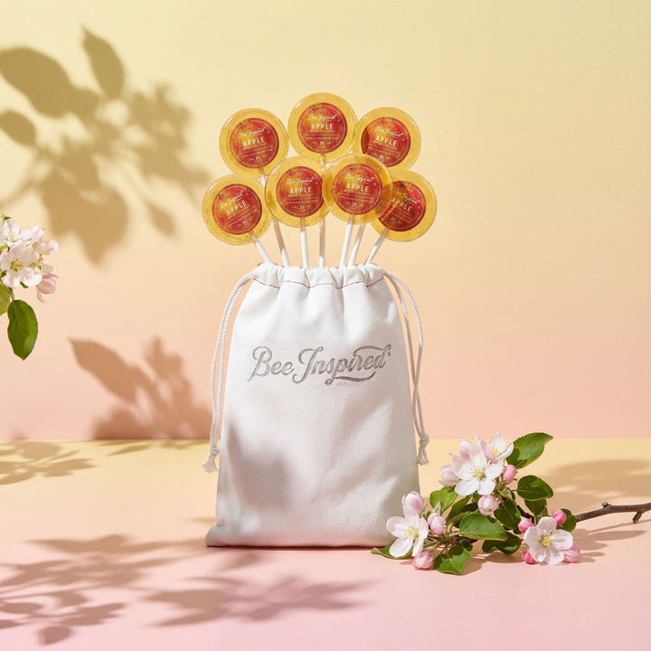 bag of 8 apples and honey lollipops in bag standing up on desk with spring of apple blossom