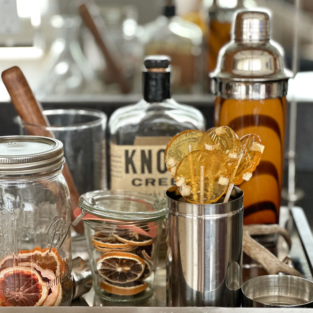 Bar set up to make drinks with a cup of apple honey lollipops and dried orange slices 