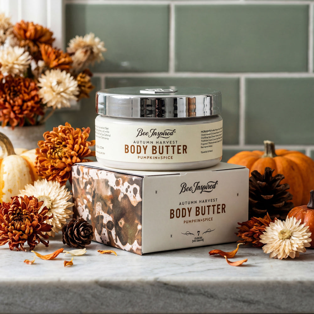 Jar of 'Bee Inspired' pumpkin spice body butter on a box with autumn-themed decorations.