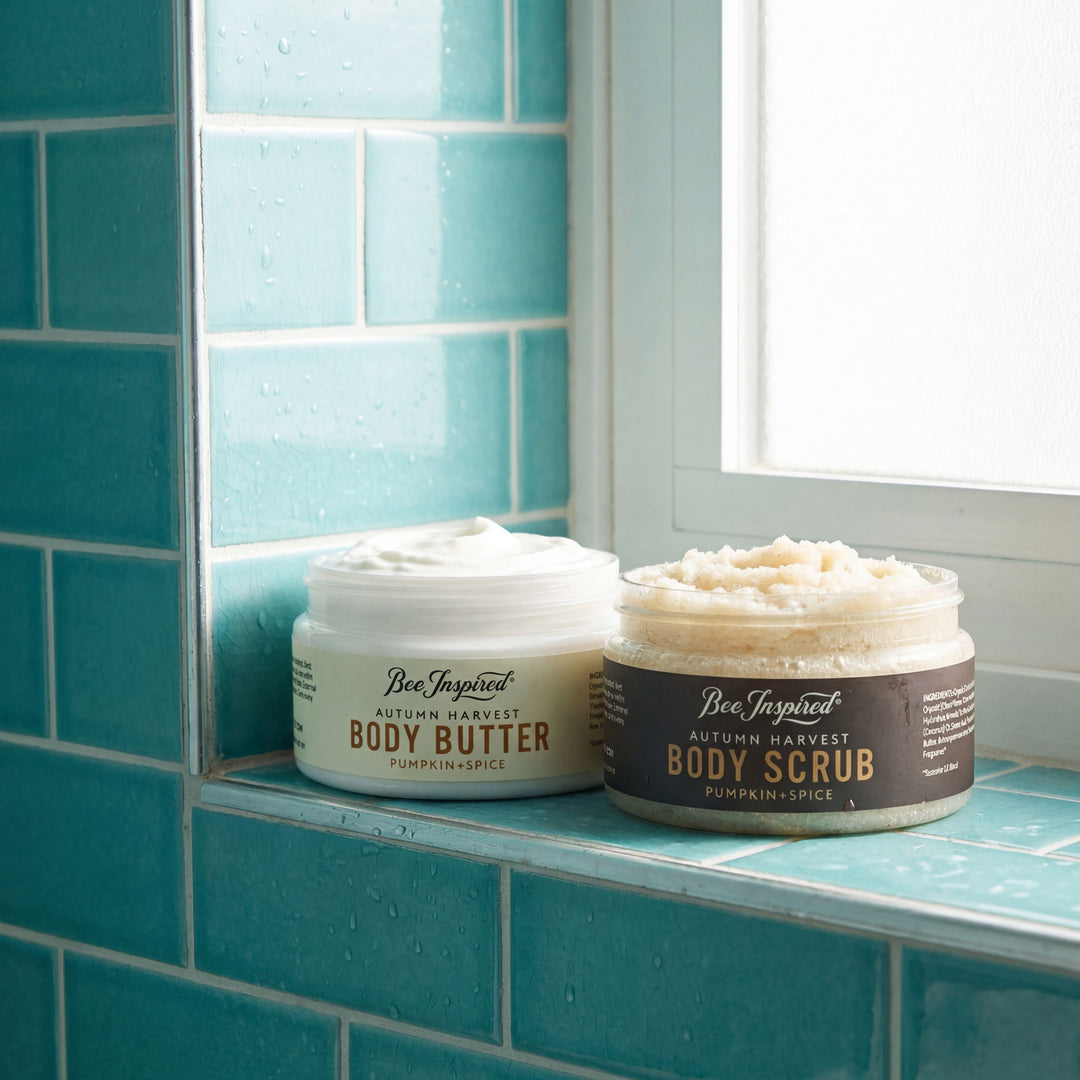 Two jars of 'Bee Inspired' body butter and scrub on a blue tiled shelf.