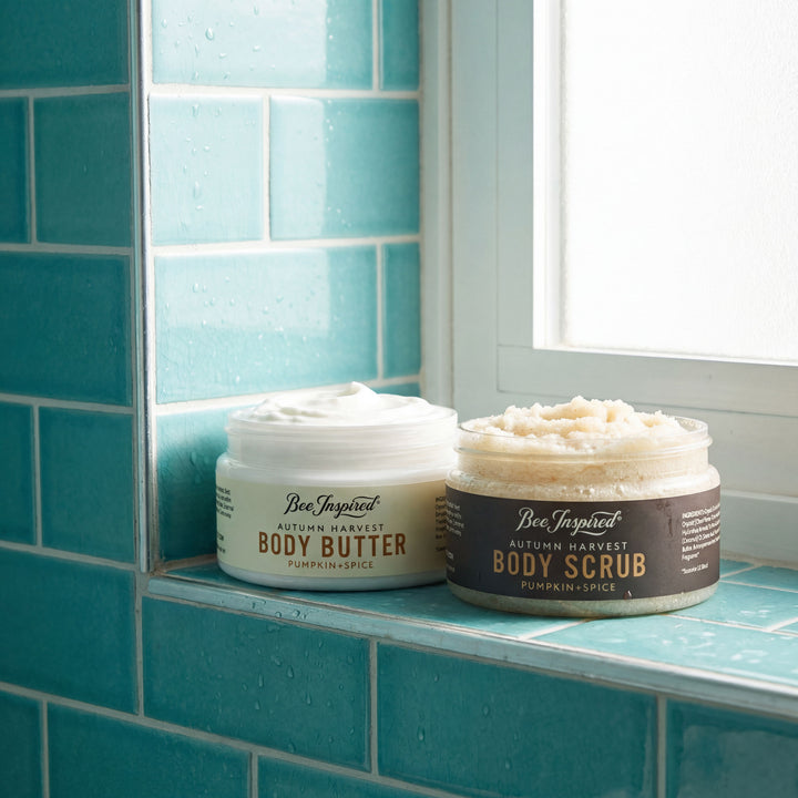 Two jars of 'Bee Inspired' body butter and scrub on a blue tiled shelf.