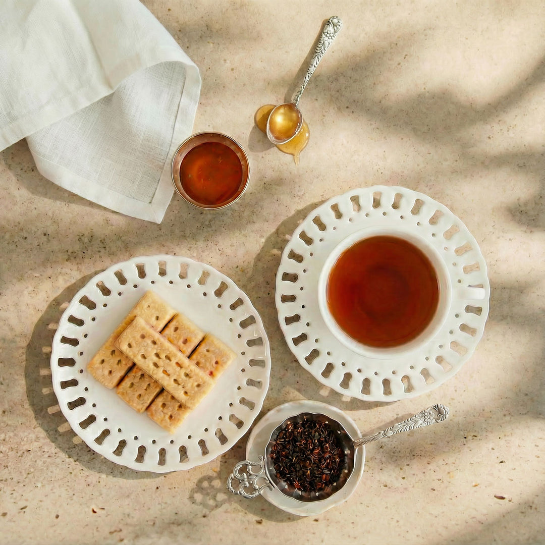 Tea set with a cup, saucer, cookies, and honey on a textured surface