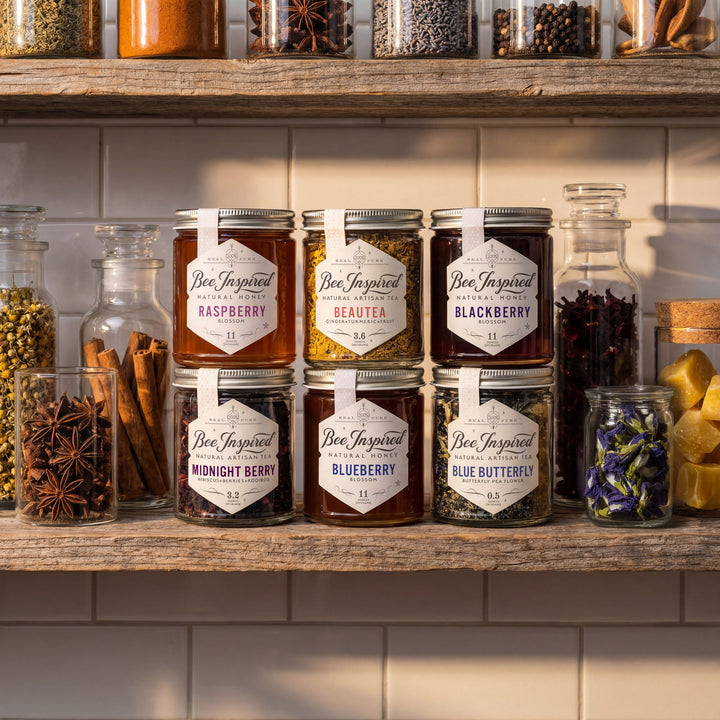 Jars of 'Bee Inspired' honey and tea on a wooden shelf with various jars of spices and grains.