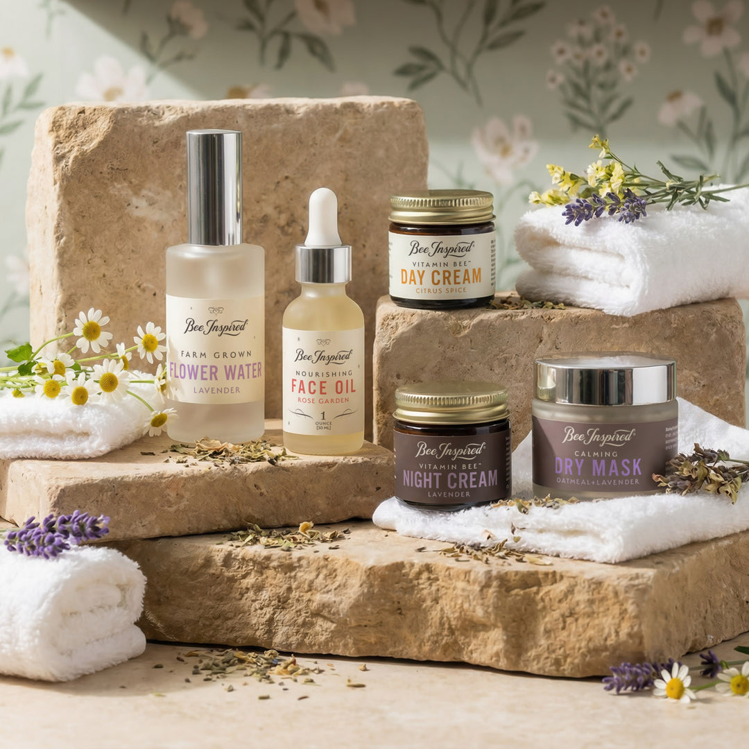 Collection of skincare products on a stone surface with flowers and towels.