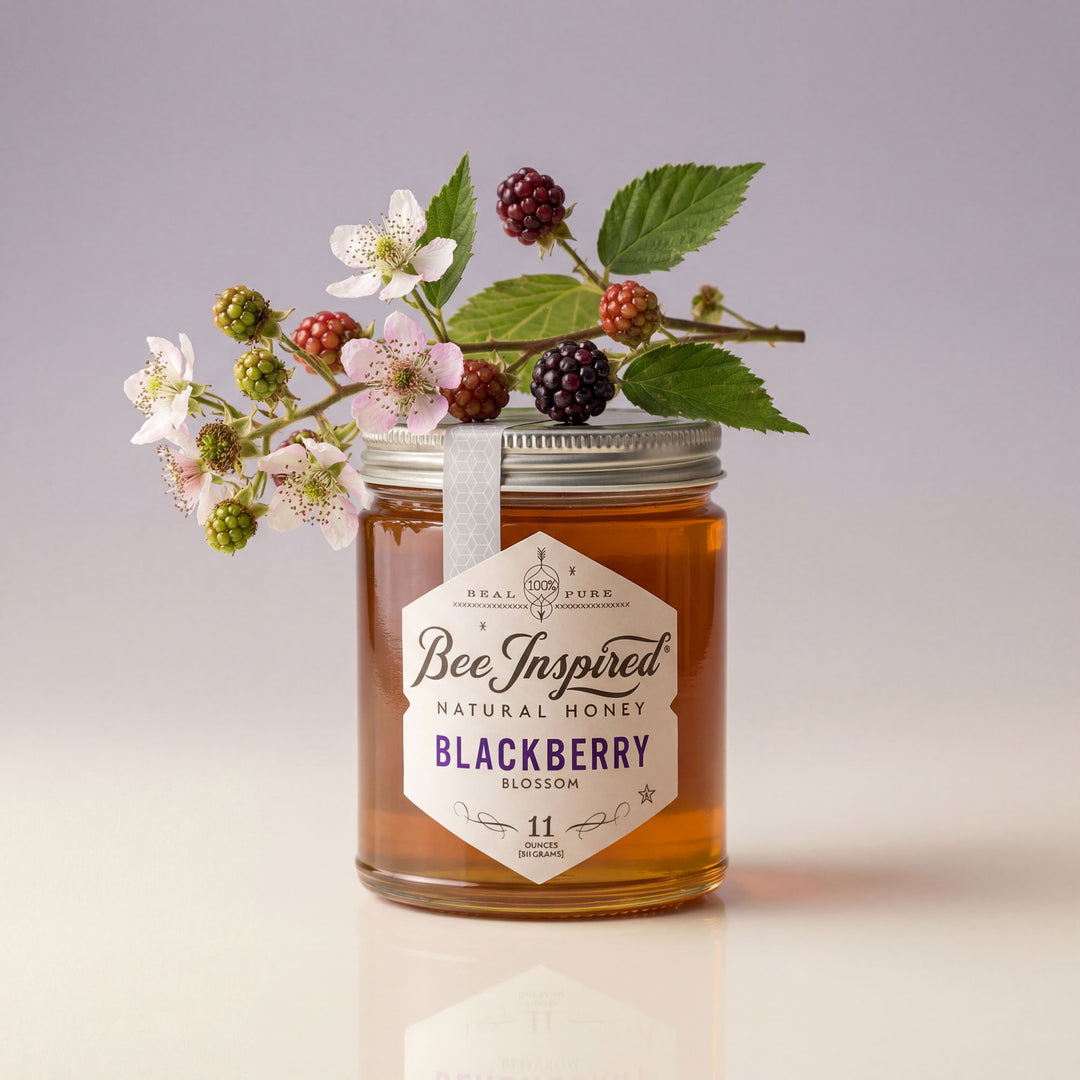 Jar of Bee Inspired Blackberry Blossom honey with flowers and berries on a light background