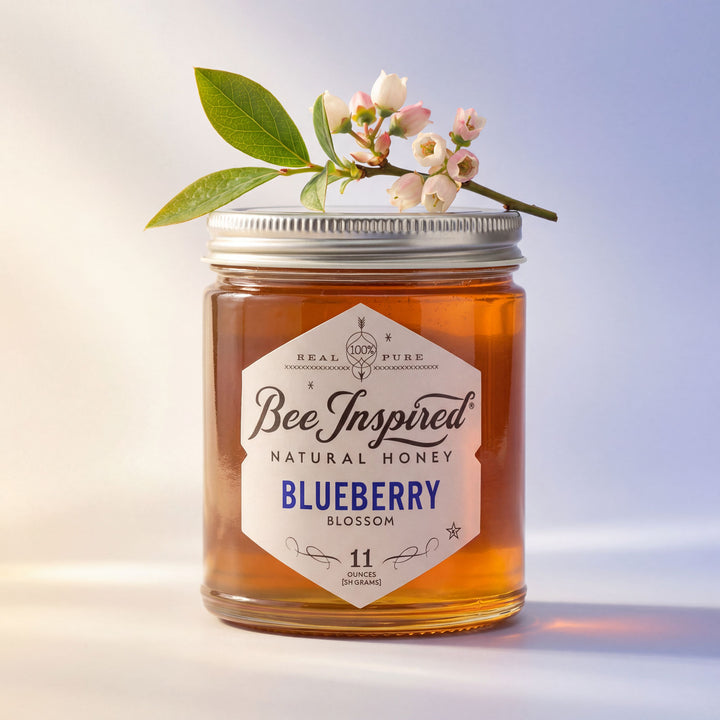 Jar of Bee Inspired Natural Honey Blueberry Blossom with a floral decoration on a light background