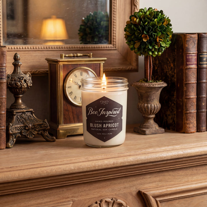 Candle labeled 'Bee Inspired' on a wooden surface with decorative items in the background