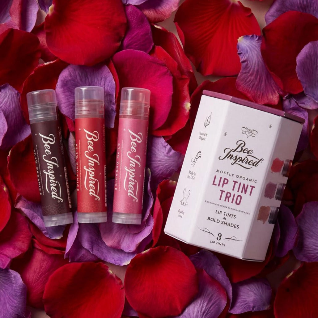 Bee Inspired lip tint trio with packaging on red and purple flower petals