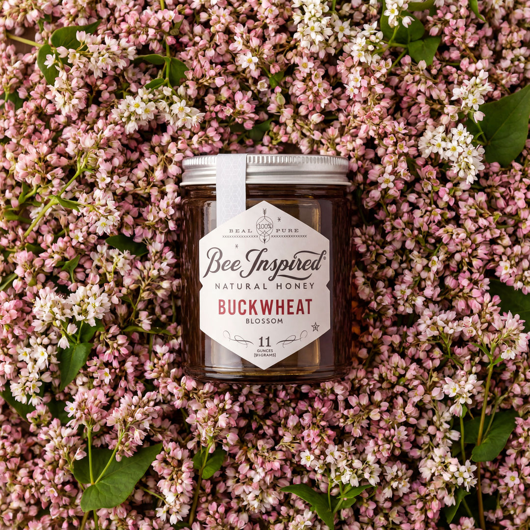 Jar of Bee Inspired natural honey surrounded by pink and white flowers