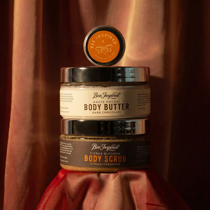 Two jars of Bee Inspired body products on a textured red fabric background