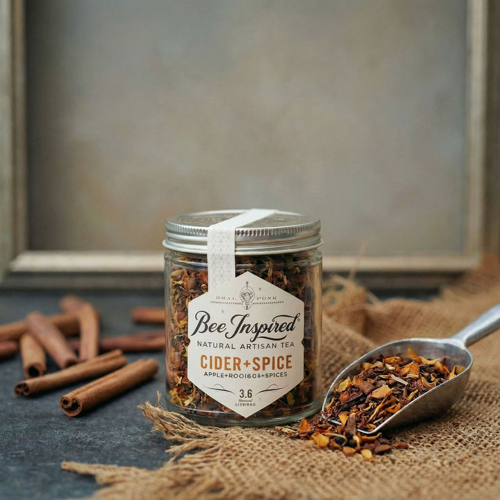 Jar of 'Bee Inspired' Cider + Spice tea with cinnamon sticks on a rustic background