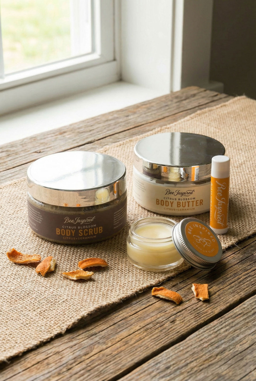 Collection of body care products including scrub, butter, and lip balm on a wooden surface.