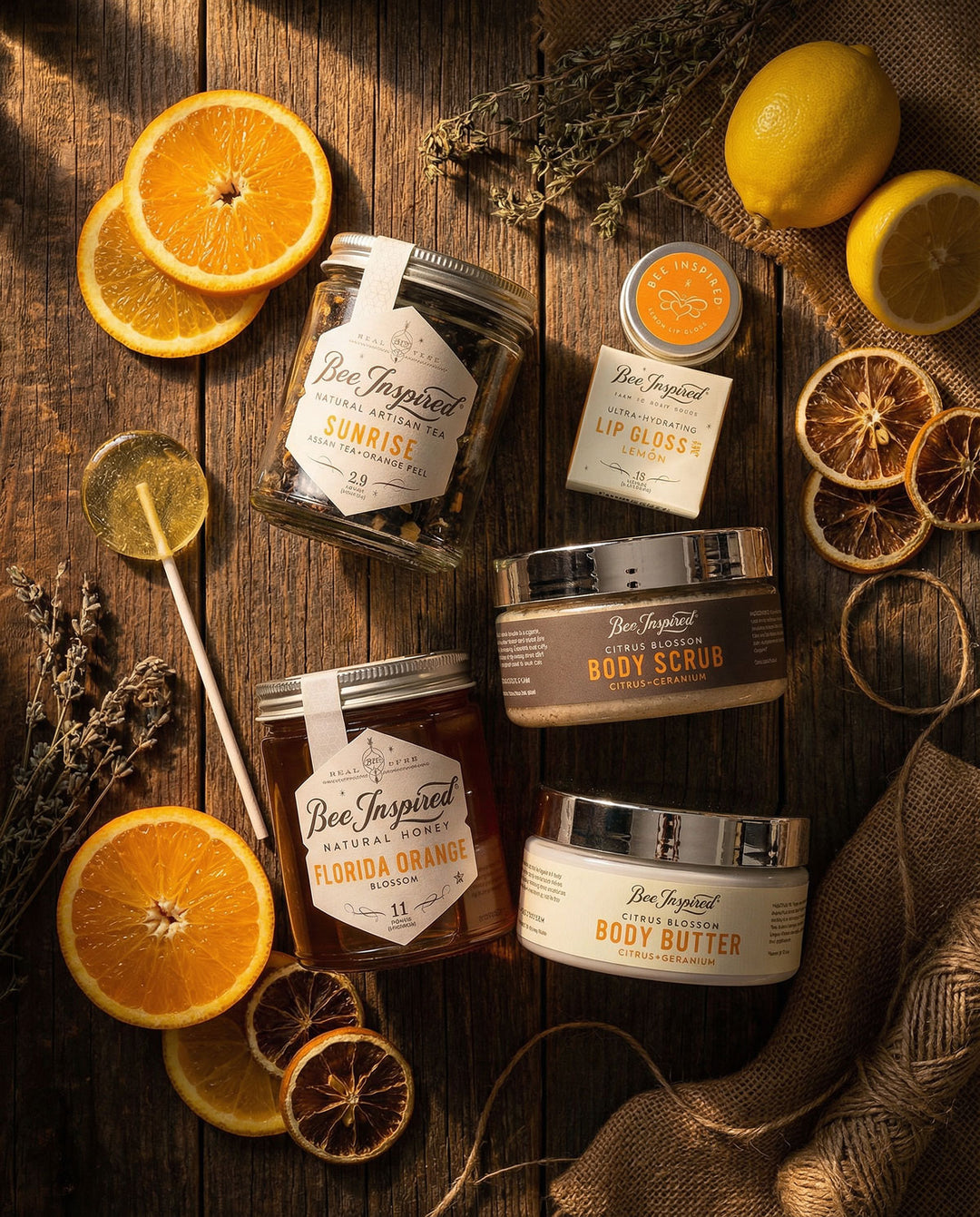 Collection of Bee Inspired skincare products on a wooden surface with oranges and lemons.