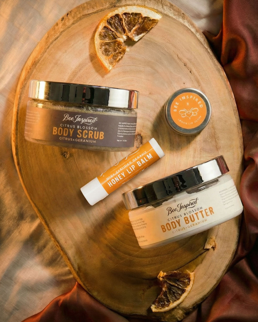 Bee Inspired skincare products on a wooden surface with dried oranges.