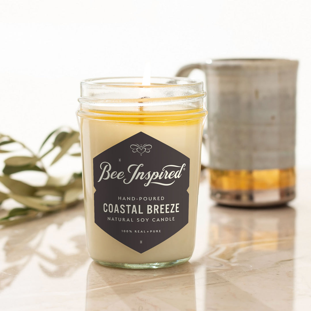 Coastal Breeze jelly jar candle burning next to mug 