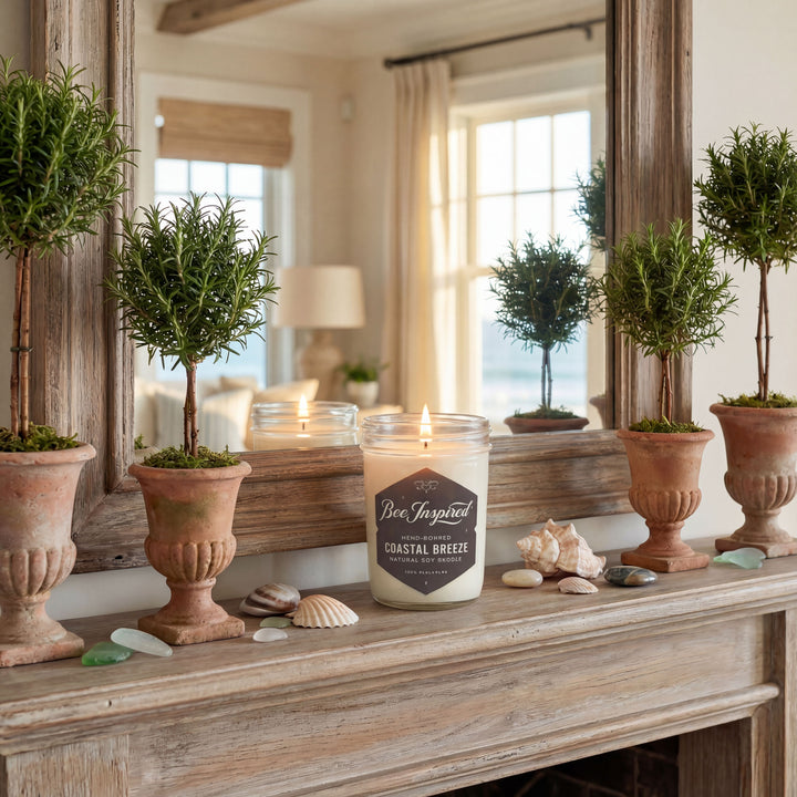 Candle with 'Be Inspired' label on a wooden surface with decorative plants and shells.
