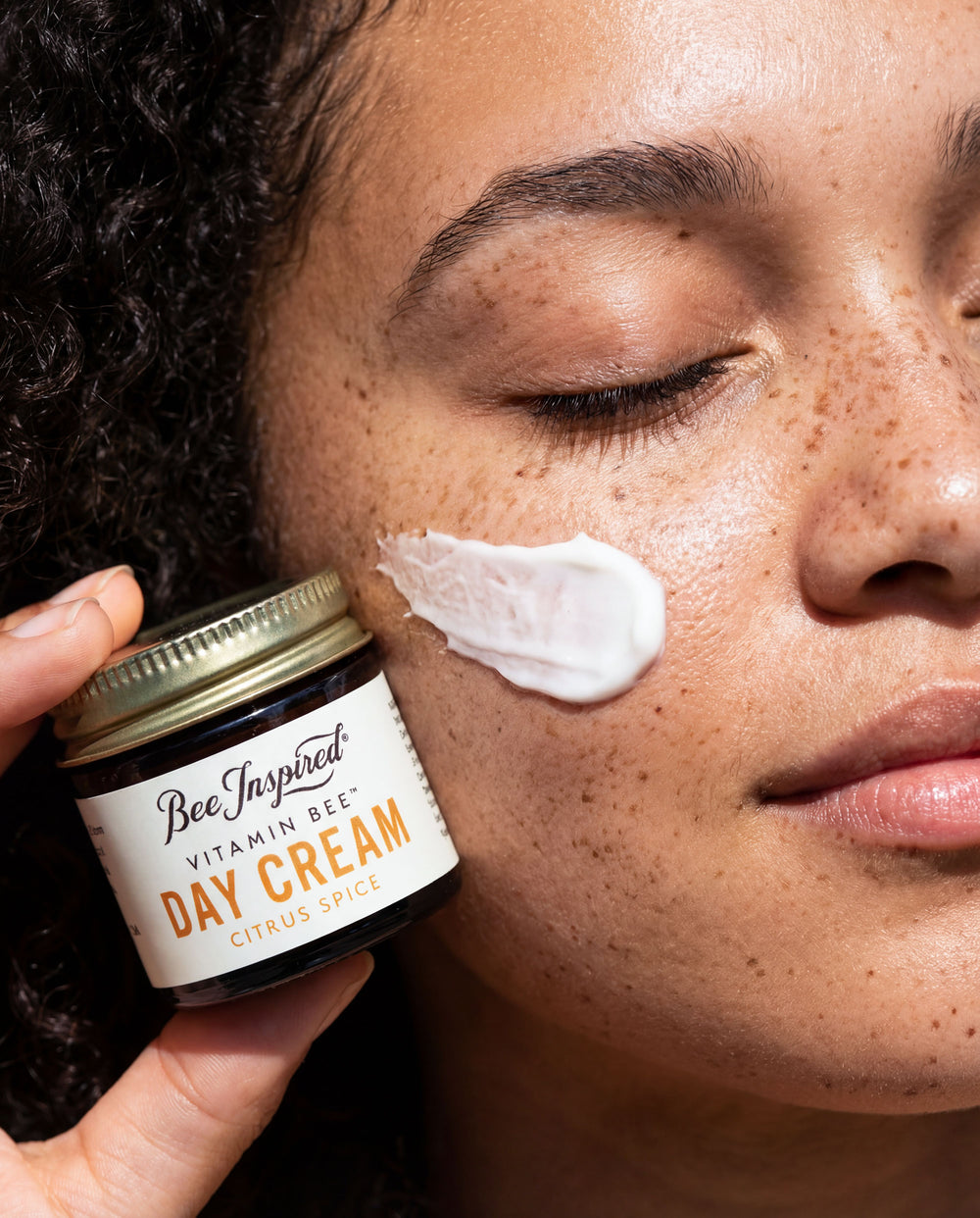 Person applying Bee Inspired Vitamin Bee Day Cream to their face
