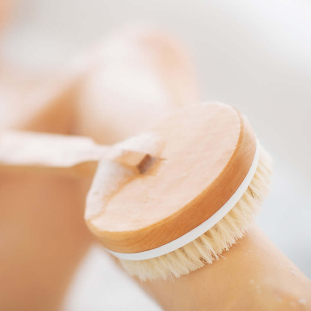 person dry brushes their leg 