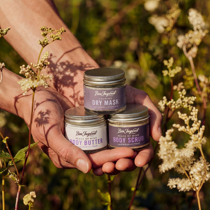 Three small containers of body care products held in hands with a natural background