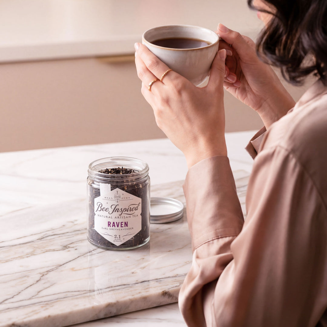 Person holding a cup of coffee with a jar labeled 'Bee Inspired' on a marble surface.