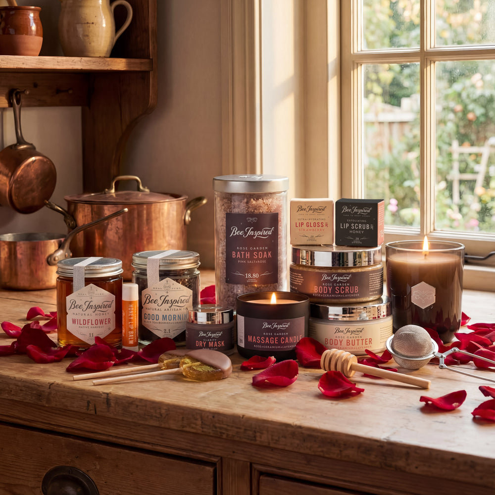 Assorted beauty products including candles, lip balms, and body scrubs on a wooden surface with a window in the background.