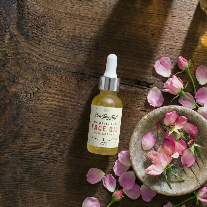 Nourishing face oil bottle with pink flowers on a wooden surface
