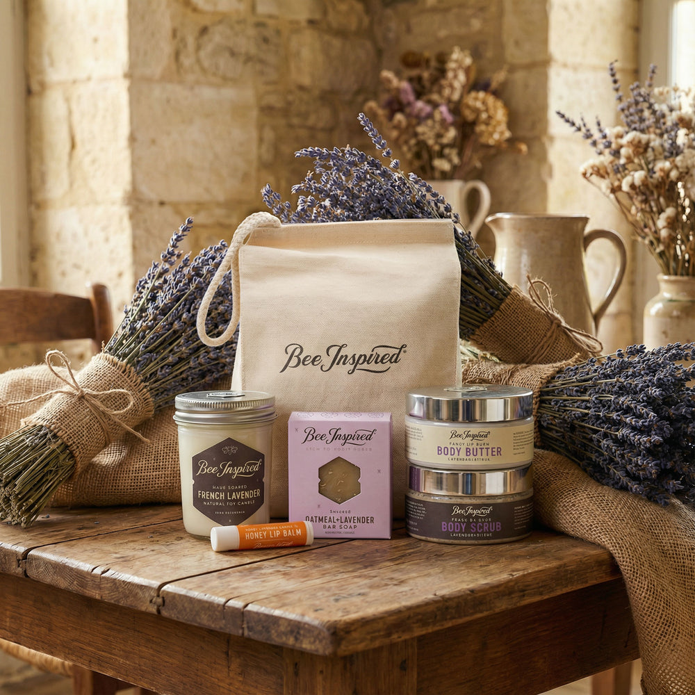 Bee-inspired products including candles, soap, and body butter on a wooden table with lavender decorations.