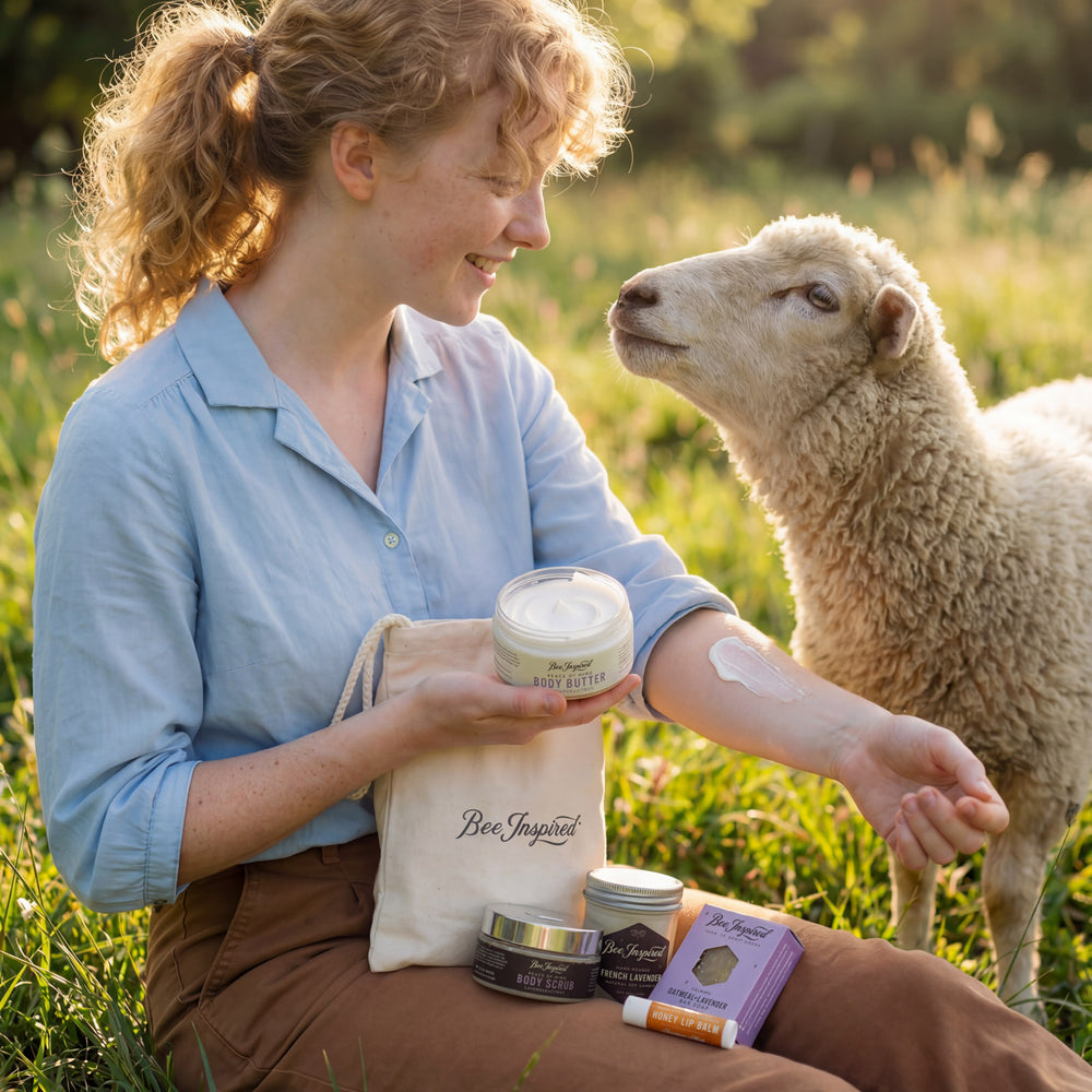 Woman applying cream to her arm with a sheep in a field, holding 'Bee Inspired' products.