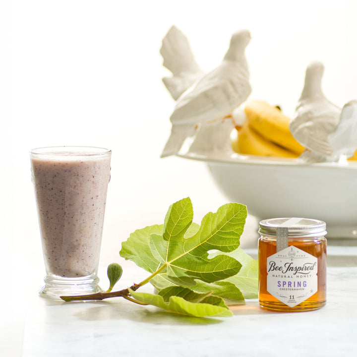 glass filled with smoothie next to a fig leaf and a jar of spring honey from bee inspired honey retail store in owings mills