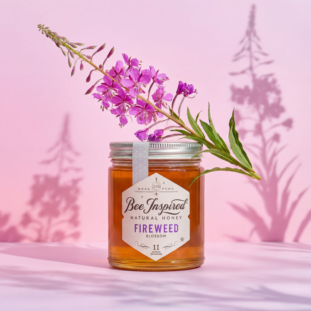 Jar of 'Bee Inspired' fireweed honey with a pink flower on a pink background