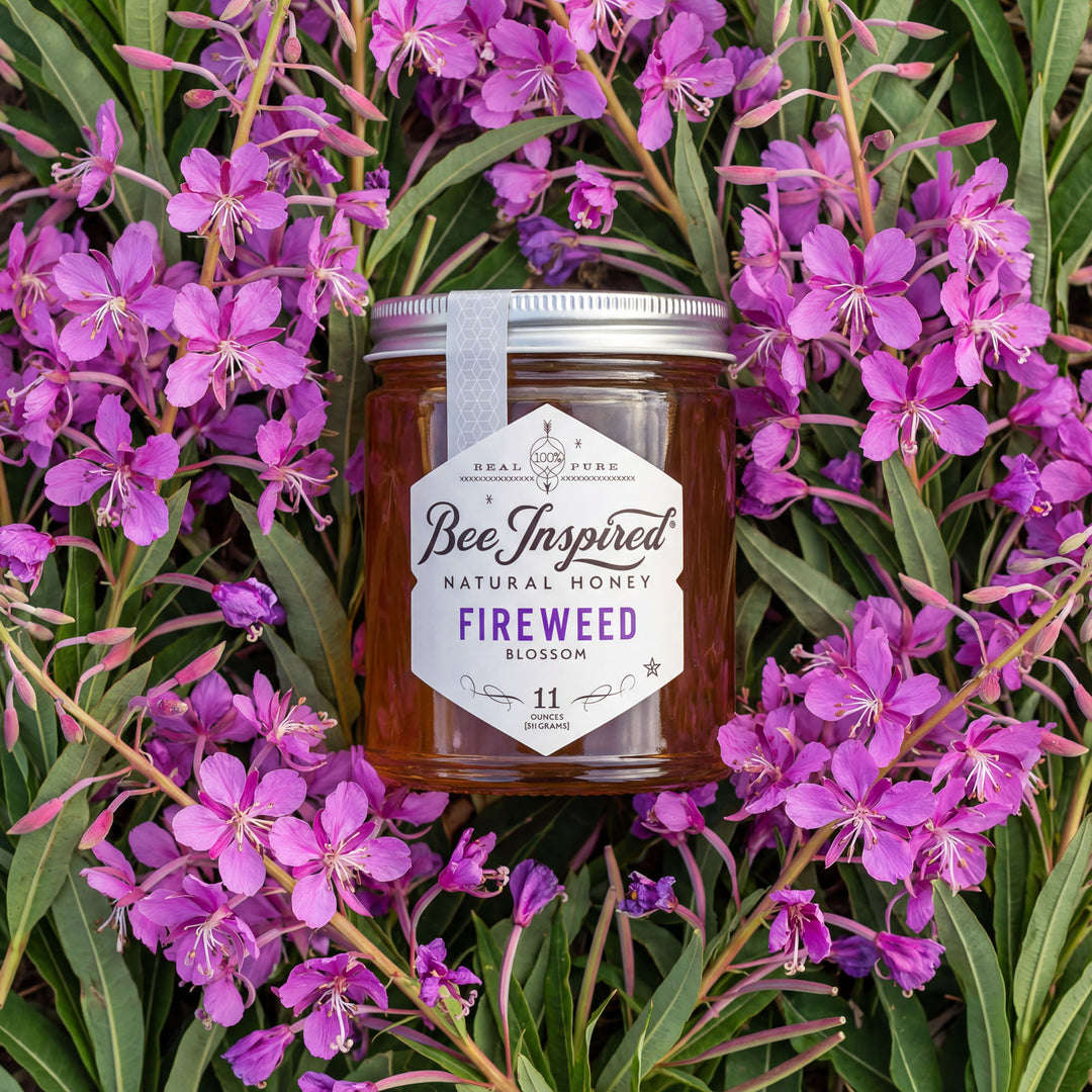 Jar of 'Bee Inspired' natural honey surrounded by purple fireweed flowers
