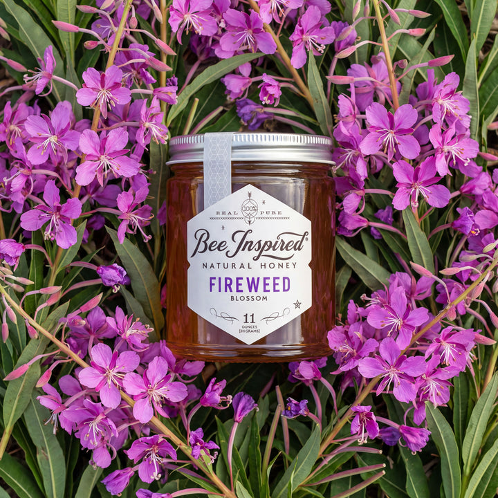Jar of 'Bee Inspired' natural honey surrounded by purple fireweed flowers