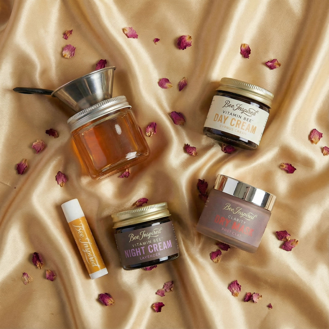 Skincare products including jars and a lip balm on a beige fabric background with dried flowers