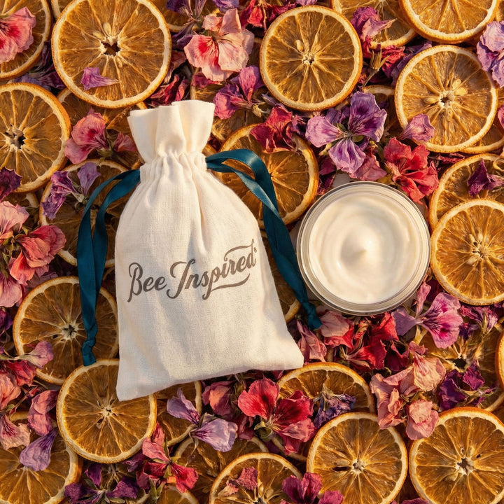 Body butter with 'Bee Inspired' bag surrounded by dried oranges and flowers

