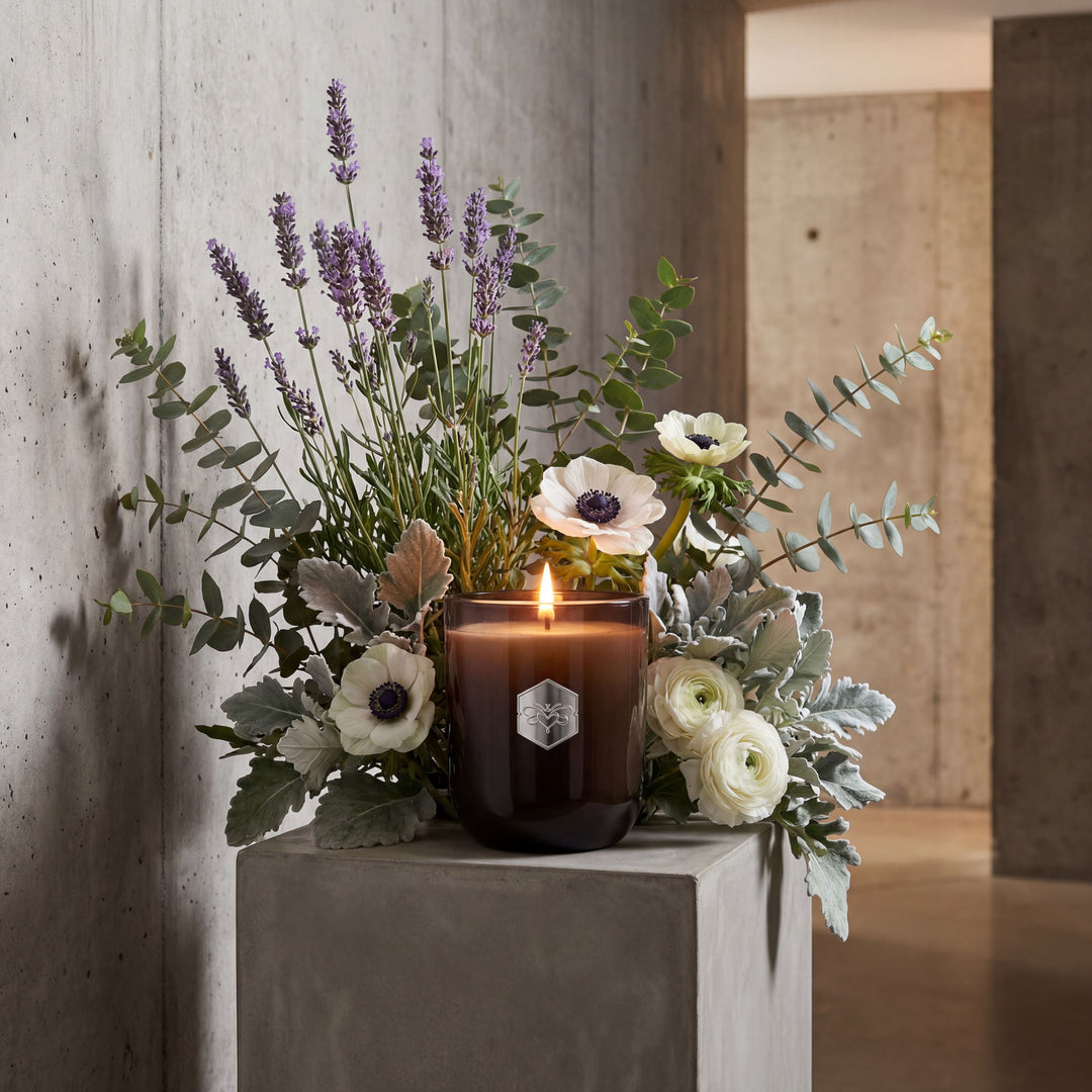 Candle with flowers on a concrete surface against a concrete wall.