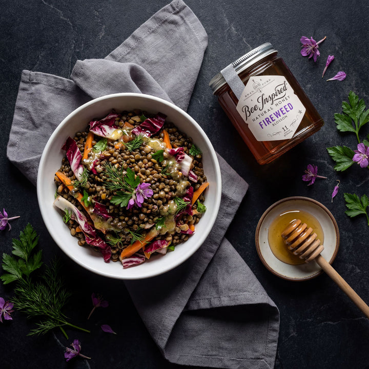 french lentil salad in white bowl on black table with bee inspired fireweed honey
