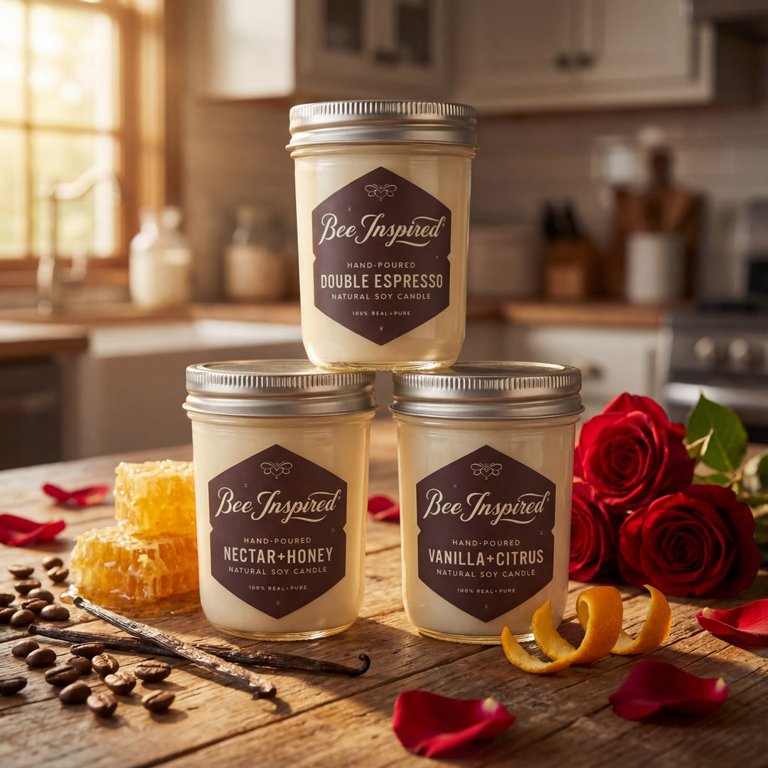 Three 'Bee Inspired' candles on a kitchen counter with flowers and ingredients.