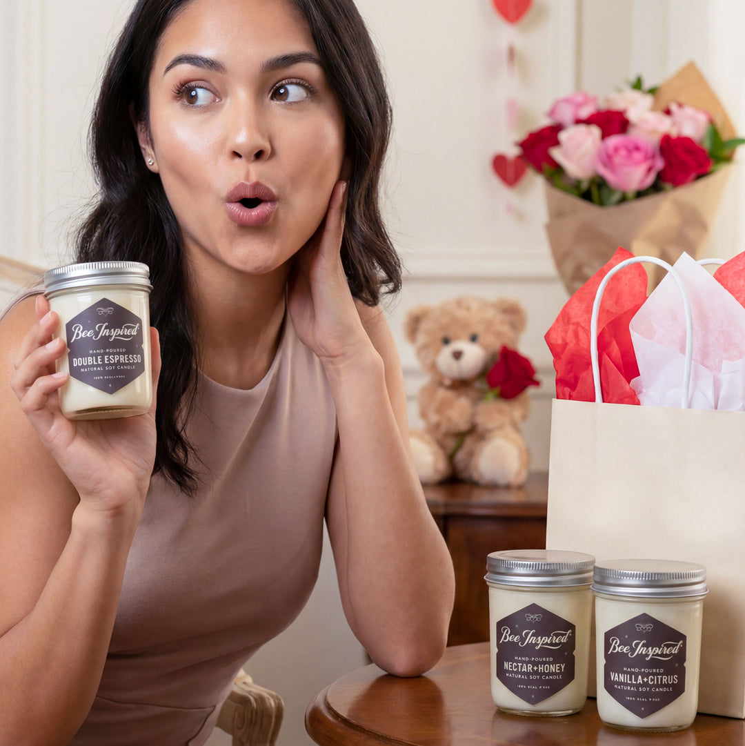 Woman holding a jar of Bee Inspired candle with a surprised expression, surrounded by more candles and a teddy bear.