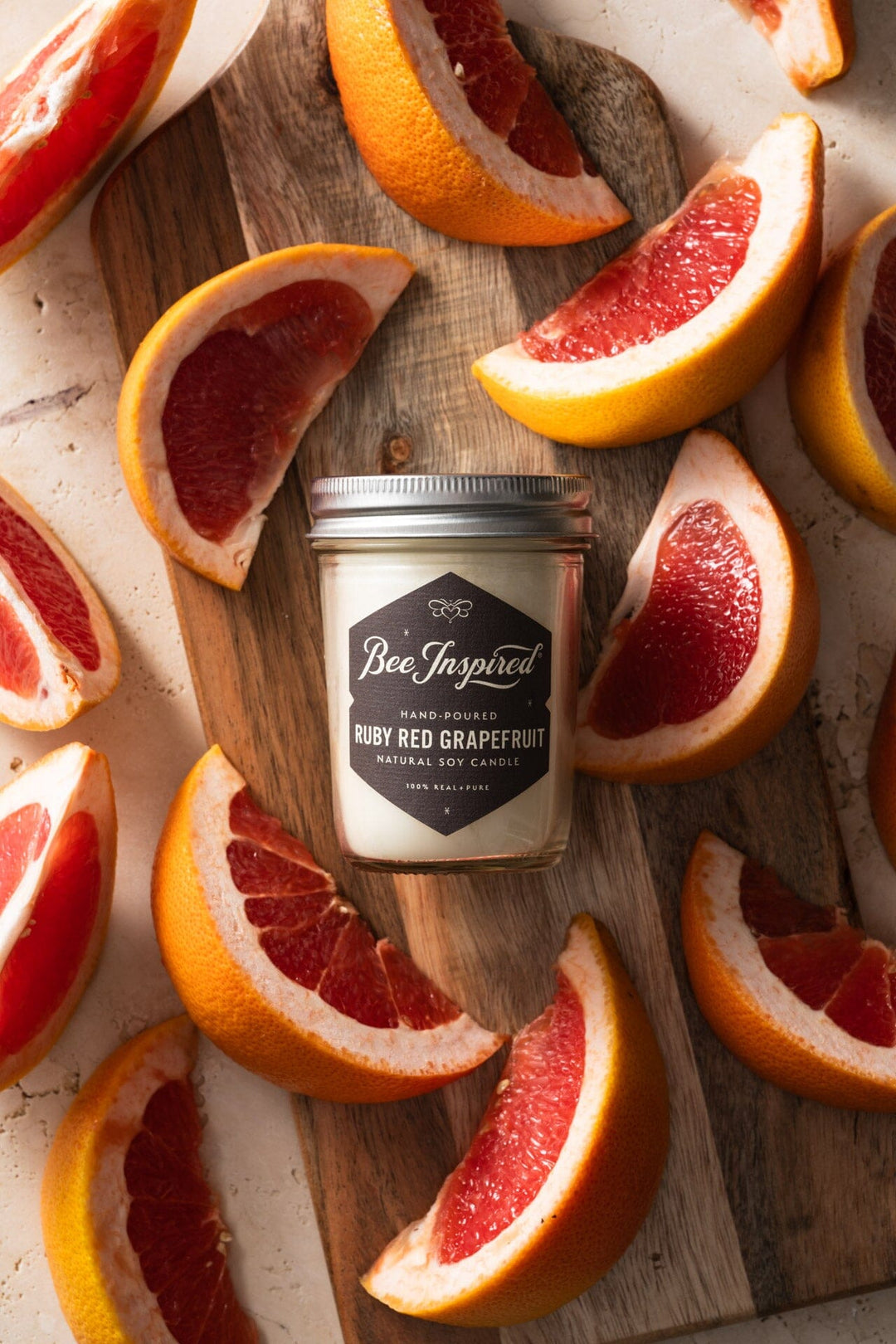Ruby Red Grapefruit Jelly Jar Candle surrounded by grapefruit on a cutting board tall pin