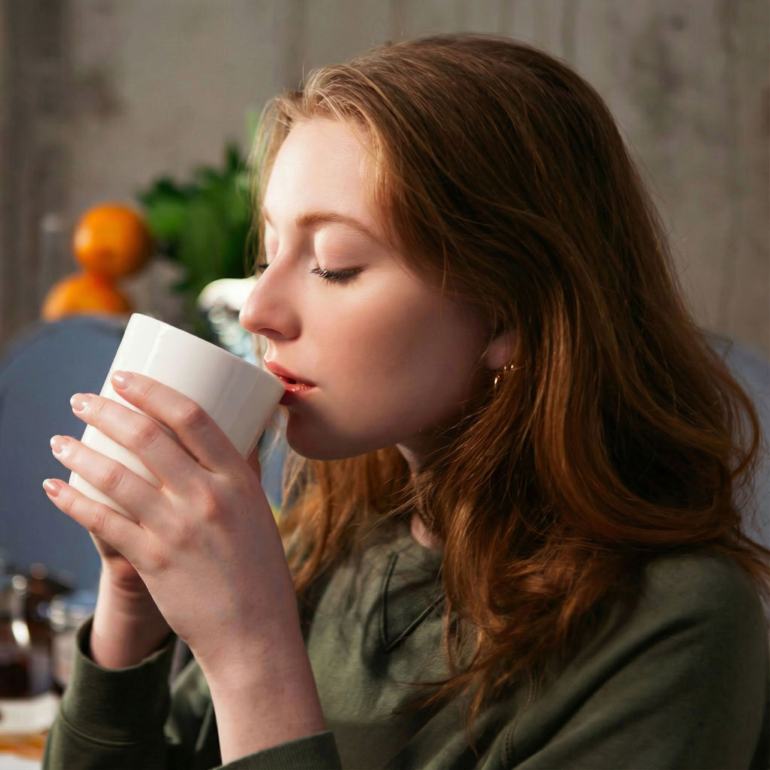 Woman drinking from a white mug in a cozy indoor setting