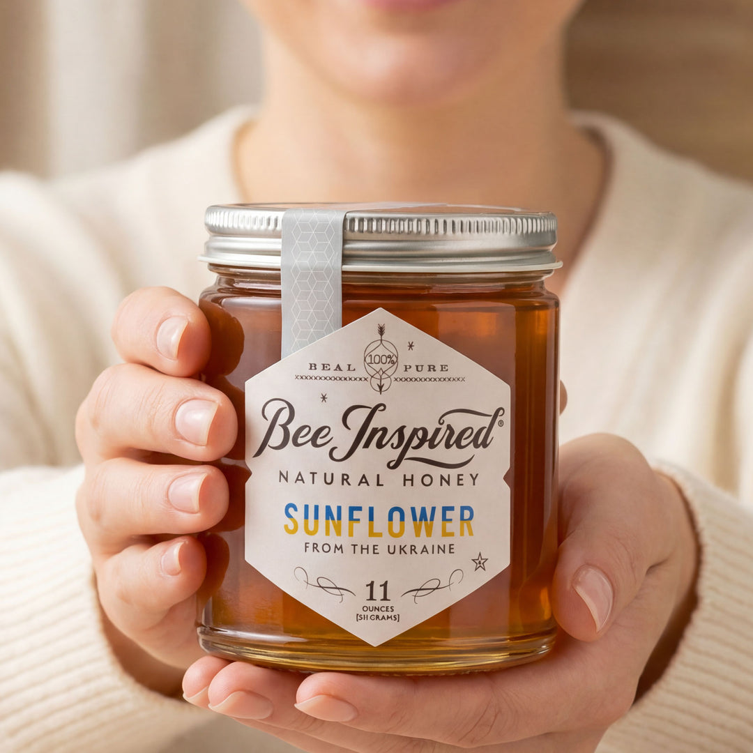 Person holding a jar of 'Bee Inspired' natural honey with a beige background