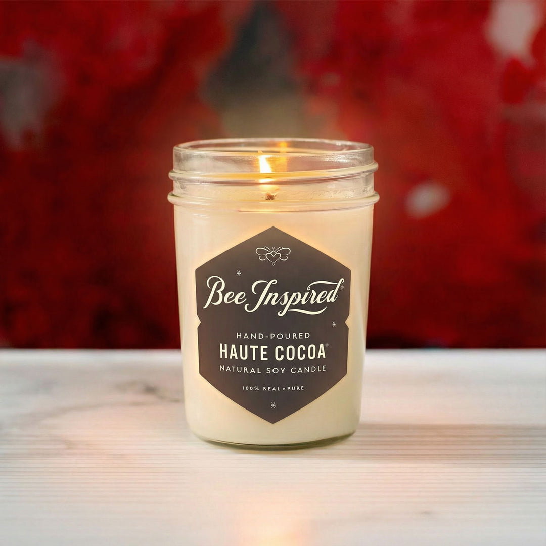 Bee Inspired jelly jar candle with a dark label on a blurred red background