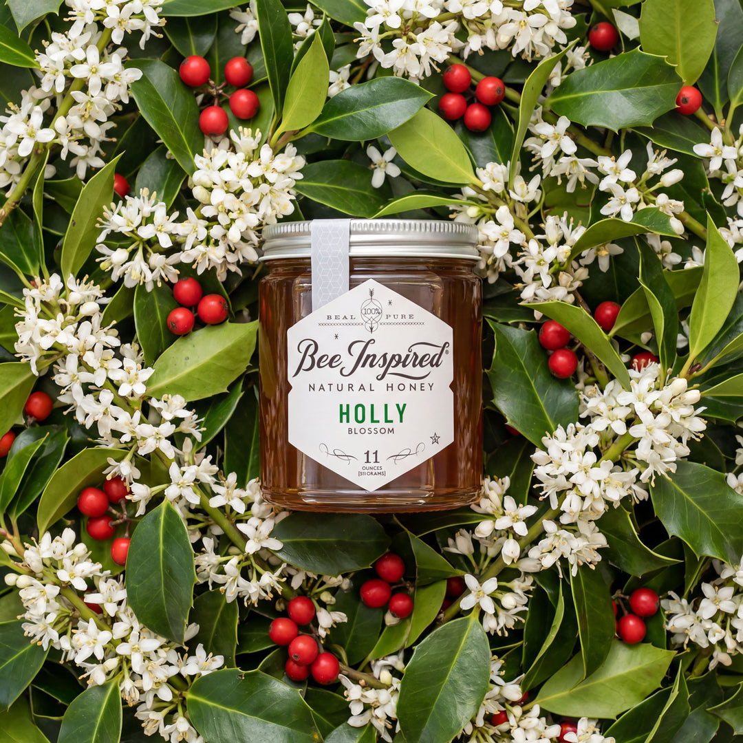 Jar of BeeInspired honey surrounded by holly leaves and berries