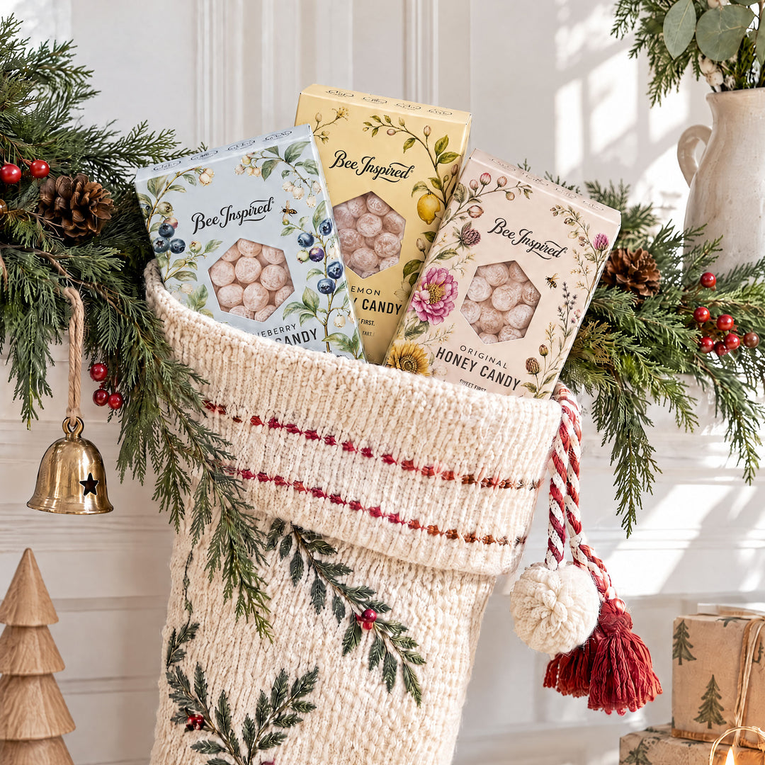 holiday stocking with boxes of Bee Inspired honey candy in it on mantle with holiday greenery