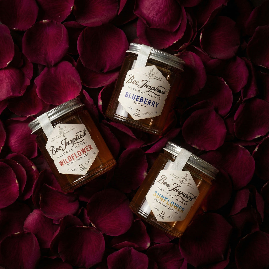 Three jars of 'Bee Inspired' honey on a bed of red rose petals