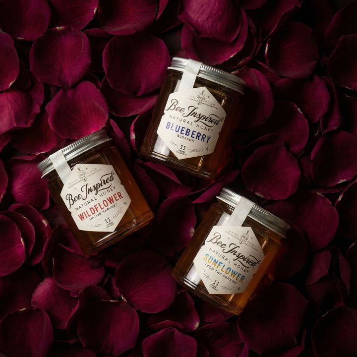 Three jars of 'Bee Inspired' honey on a bed of red rose petals
