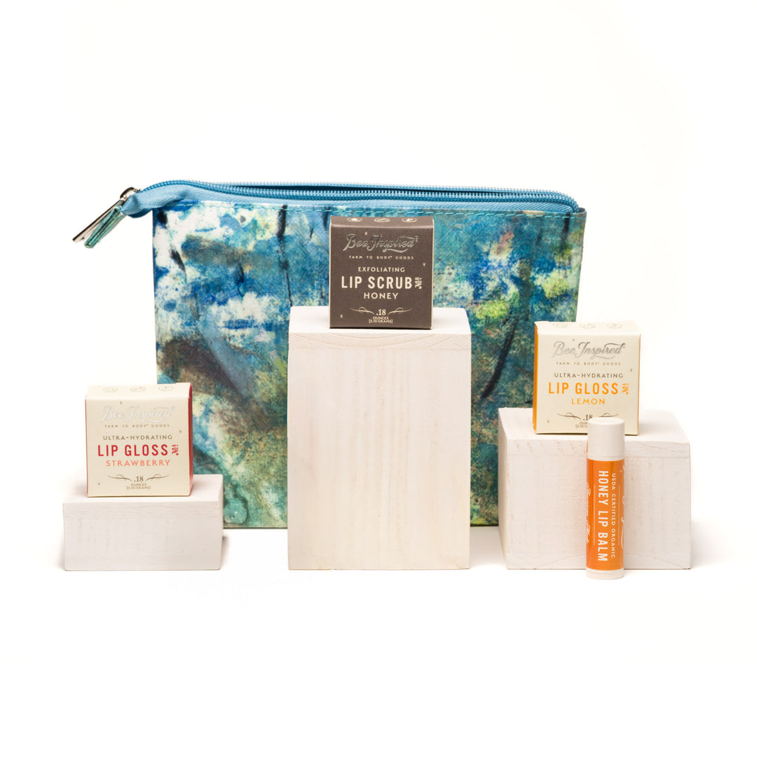 Collection of lip care products including lip glosses and scrubs with a blue floral pouch on a white background.